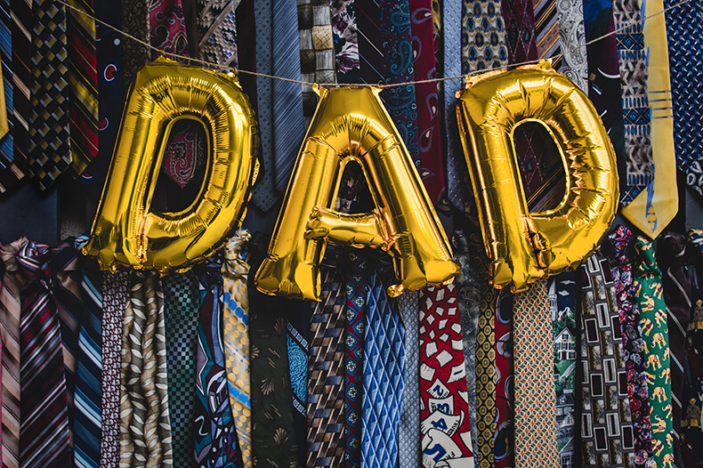 Värikkäitä kravaatteja riveissä, joiden päällä teksti dad kultaisilla kirjaimilla.