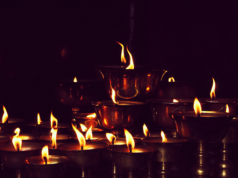 Useita kynttilöitä palamassa tummaa taustaa vasten.