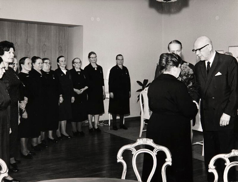 Mustavalkoinen kuva äitienpäivän kunniamerkkien jakamisesta, kuvassa myös presidentti Urho Kekkonen.
