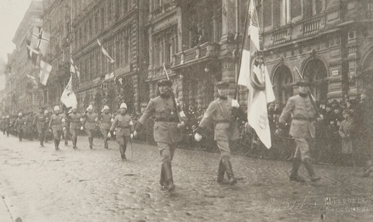 Itsenäisyyspäivän paraati 1919, sotilaita marssimassa Suomen lippujen kanssa.