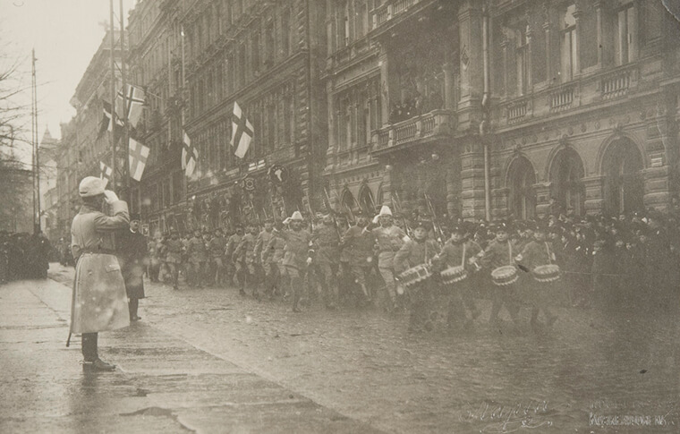 Mustavalkoinen kuva itsenäisyyspäivän paraatista vuodelta 1919, eversti von Essen tervehtii ohimarssivia sotilaita.