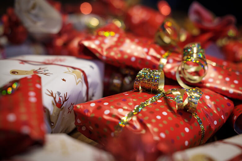 Punaisin, valkoisin ja kultaisin käärein paketoituja joululahjoa, koristeena kaunis kultainen lahjanauha.