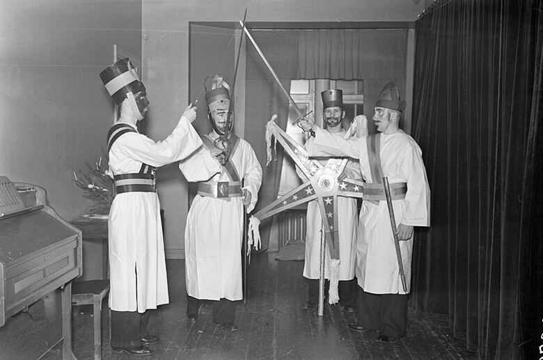 Mustavalkoinen kuva neljästä pojasta eli tiernapojista esiintymässä Helsingin yliopiston Pohjois-Pohjalaisen osakunnan joulujuhlassa.