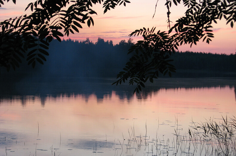 Auringonlasku loppukesästä järvimaisemassa.
