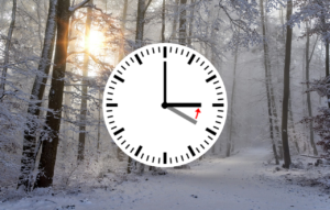 Talvinen metsämaisema ja kellotaulu, jossa kuvataan kellojen siirtoa tunti taaksepäin, eli kello neljästä kello kolmeen.