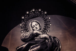 Taiteellinen näkemys neitsyt Mariasta tummalla taustalla.