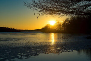 Keväinen järvimaisema auringonlaskun aikaan.